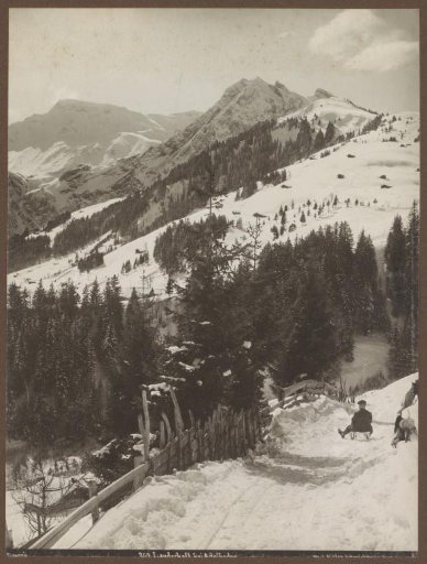 View of the snow-covered mountain slopes of Adelboden with a man on a sled on the right
