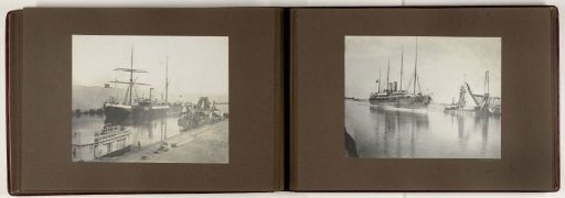 Ship sails through the Suez Canal near a dredger and a quay