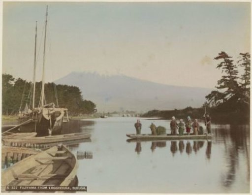 Mount Fuji seen across a body of water near Tagonoura, with people in a boat in the foreground