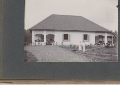 Man and woman posing in a garden before a dwelling house, presumably on the grounds of a hospital in the Dutch East Indies