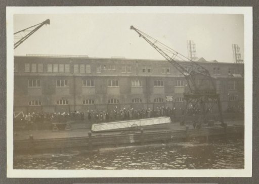 Waving people, a crane, and a rope on a quay