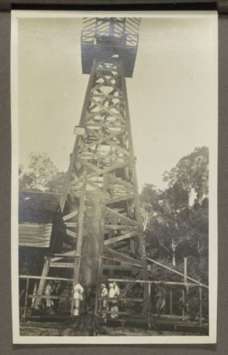 Men in tropical clothing at the foot of a drilling rig