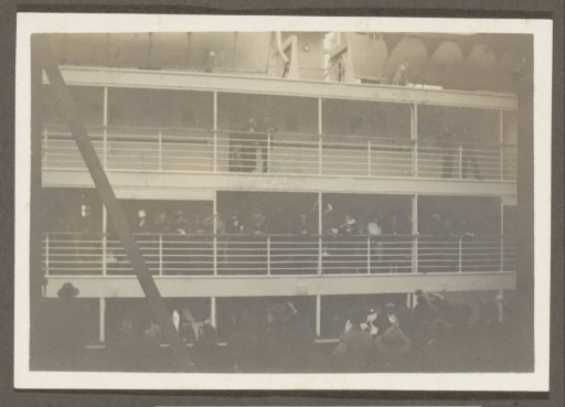 Waving passengers on a ship and onlookers on a quay