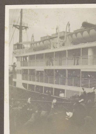 Waving passengers on a ship and onlookers on a quay