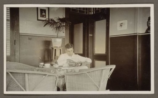 Man drinking tea with a biscuit tin in his hand