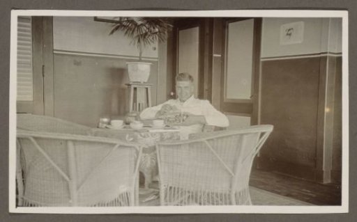 Man drinking tea with a cookie tin and a cookie in his hand