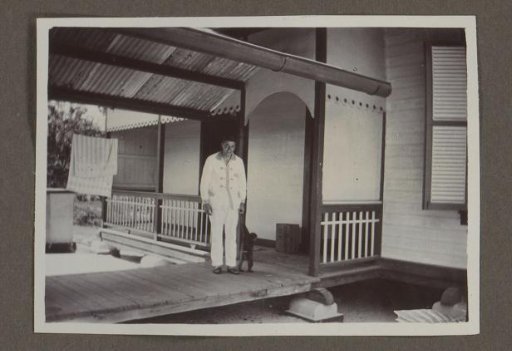 Man with a leashed meerkat on a veranda