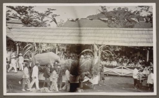 Parade with pageant wagons and participants before a tribune