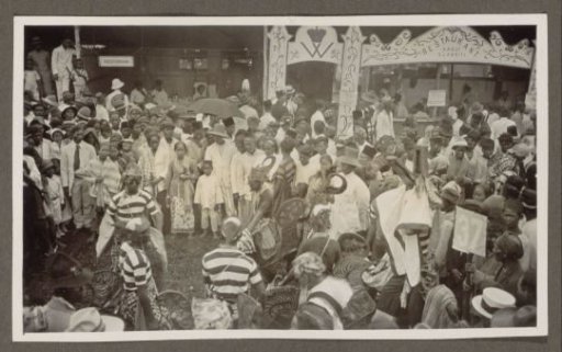 Participants in a parade and spectators before a restaurant