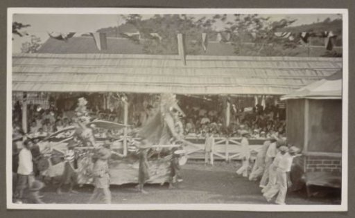 Parade with pageant wagons and participants before a tribune