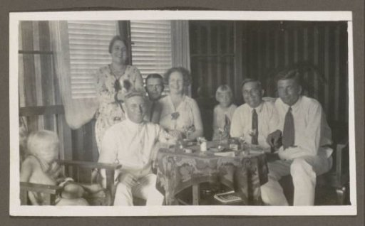 Men, women and children around a table with wine glasses