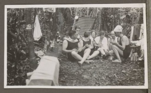 Group of men and women in swimwear in a forest, drinking