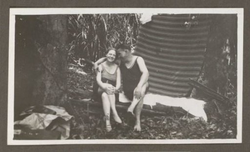 Man and woman in swimwear on a bench in a forest