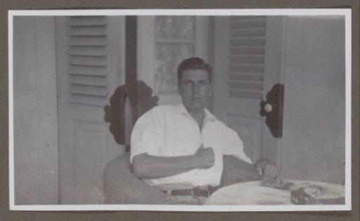 Man in a white shirt seated in a wicker chair, seen from the front