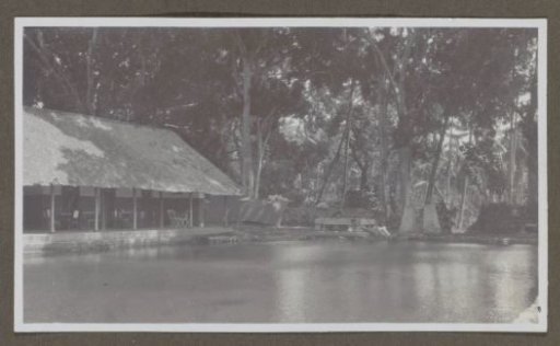 Building with covered seating by a waterway, possibly a hospitality establishment