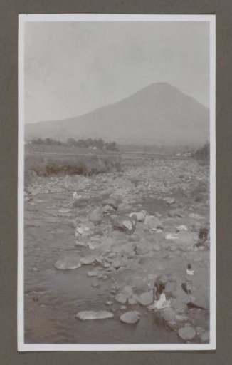 Volcano with people by a stream in the foreground