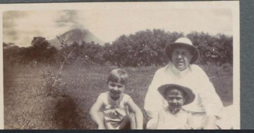 Man with children in a field in Sumatra, a volcano in the background