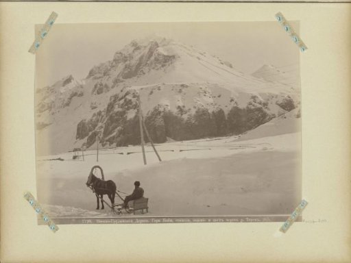 Man on a horse-drawn sleigh at the foot of a mountain on the military road of Georgia