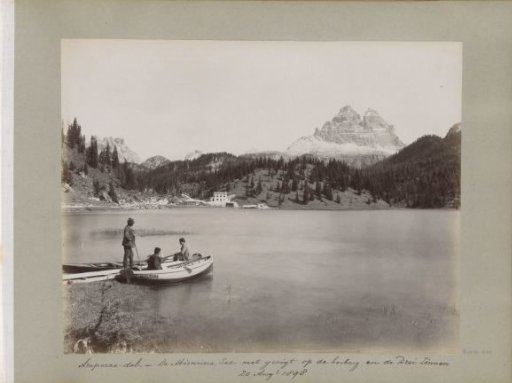 View of Lake Misurina with three men by rowing boats, an inn, and the Drei Zinnen
