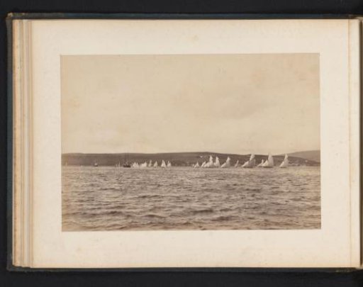 Various sailing ships afloat with a hilly landscape in the background