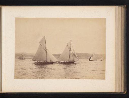 Various sailing ships, including Woodcock and Yvonne, afloat with a hilly landscape in the background