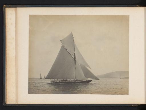 Sailing ship the Queen afloat with other sailing ships and a hill in the background