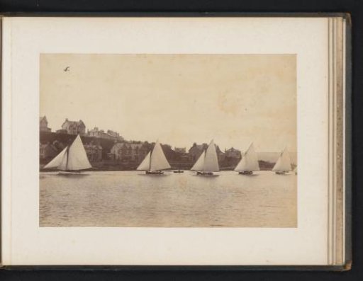 Various sailing ships, including the Astore, Dorothy and Caprice, afloat with buildings in the background