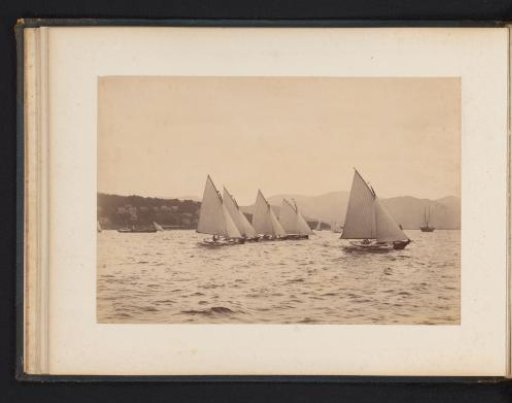 Various sailing ships afloat with a hilly landscape in the background