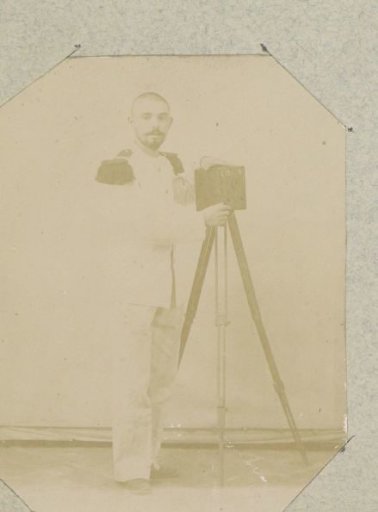 Portrait of a man in a uniform with braids standing next to a camera on a tripod