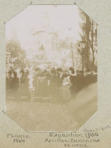 Visitors to the 1900 World's Fair in front of an illuminated glass pavilion in Paris