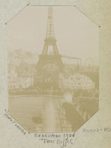 View of the Eiffel Tower during the 1900 World's Fair with Smoking Chimneys and a Ferris Wheel in the Background