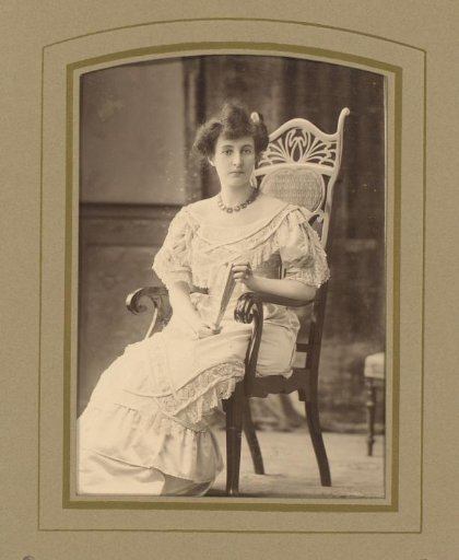 Portrait of a woman seated on a chair with a fan in her hand