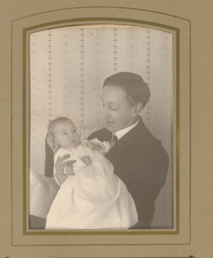 Portrait of a seated young man holding a baby in his arms