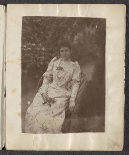 Portrait of a woman in a dress with a plant motif and flowers in her hand