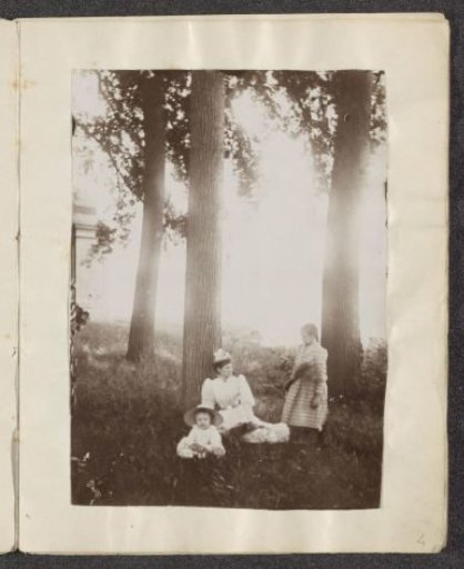 Woman and two children sitting among trees
