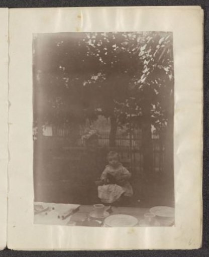 Woman and a child sitting at a wooden table in a garden