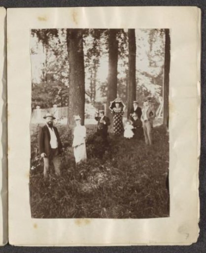 Men, women and a child posing by trees