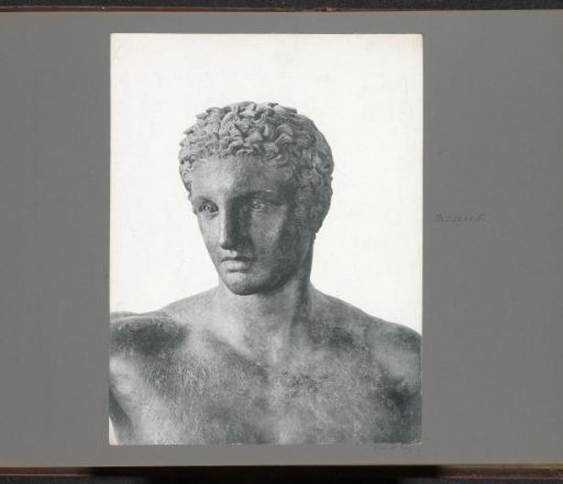 Part of an antique bronze statue of a young man (upper and front view), presumably in a museum in Athens