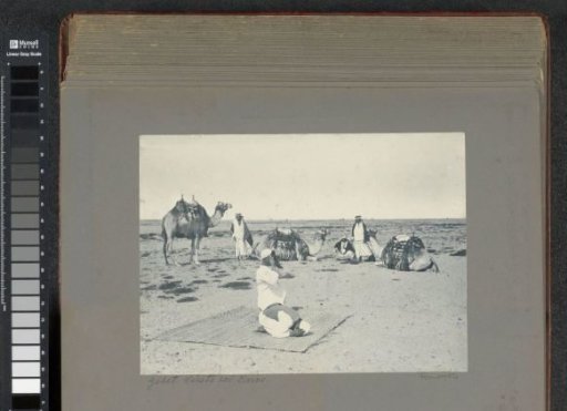 Camels and men in the desert near Cairo, in the foreground two praying men