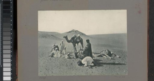 Camels and men in the desert near Cairo, in the foreground a praying man