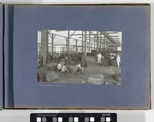 Men and women pressing and sewing up tobacco bales in a shed on Sumatra