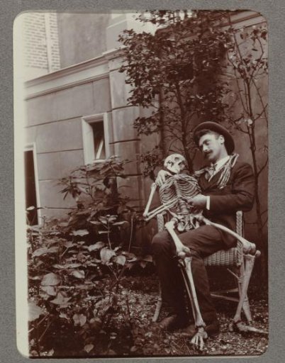 Man sitting in a garden with a skeleton on his lap
