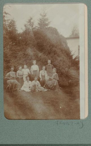 Group portrait of a company on a grassy field with two deer