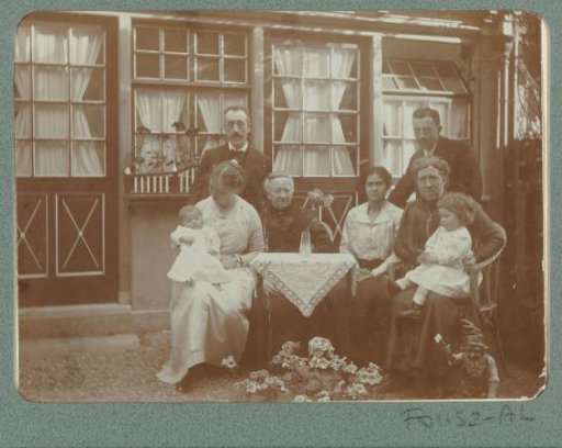 Group portrait of a family at a table in front of a house, with Christiaan Otto Roelofs at the back left