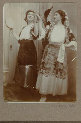 Portrait of two women in costume, one with a tambourine