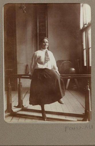 Portrait of a woman in a gymnasium, sitting on the parallel bars