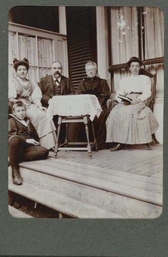 Group portrait of a family, sitting on a veranda