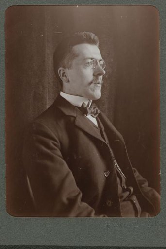 Portrait of a seated man with spectacles