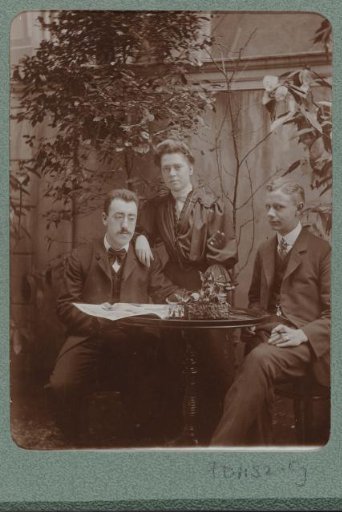 Group portrait with Christiaan Otto Roelofs on the left, a woman and a man around a table in the garden