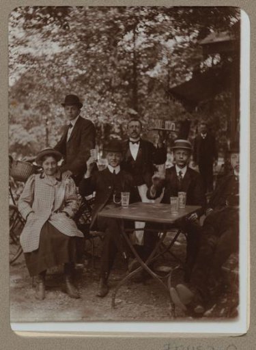 Group portrait of beer-drinking men and a woman on a terrace